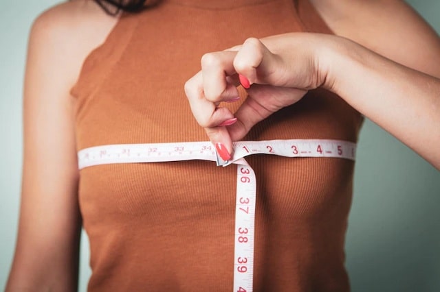 Slim femme mesure sa poitrine avec un ruban à mesurer