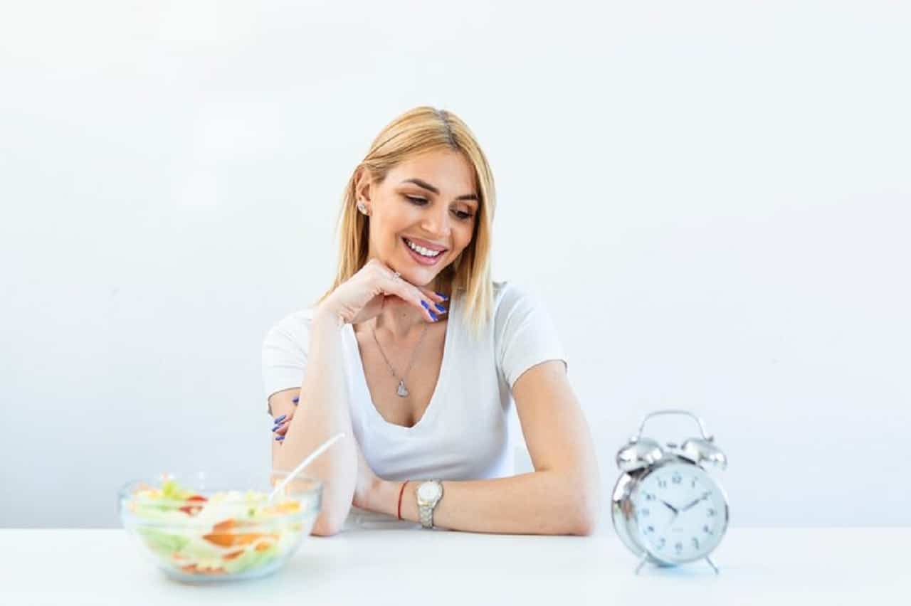 jeune femme tenant une horloge et une alimentation saine.jpg