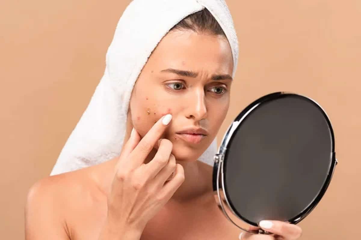 une femme regardant des acnes sur ses visages dans le mirroir.jpg