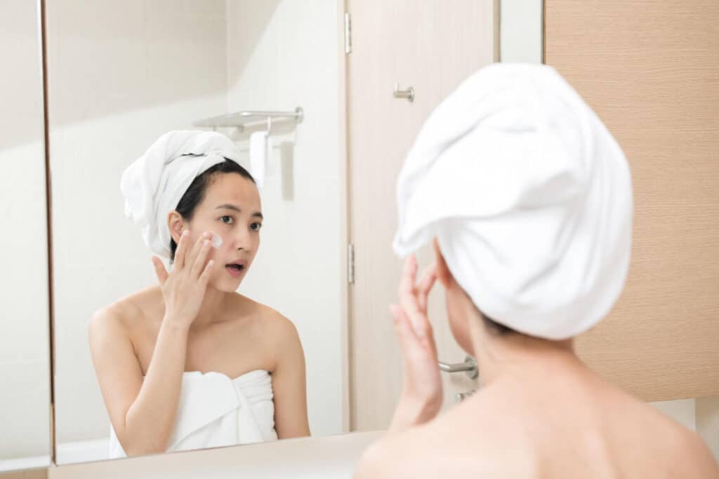 une femme devant le miroir met de la crème liftante
